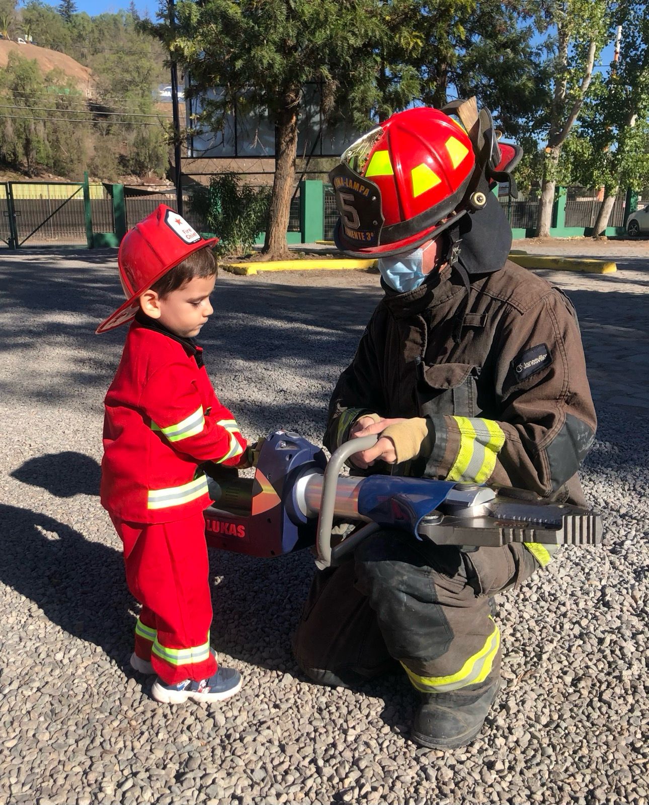 Niño disfrazado de bombero junto a bombero real