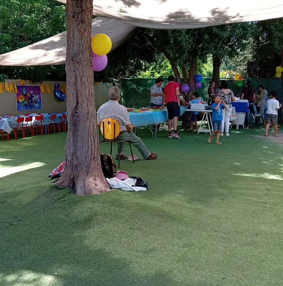 Patio de GirasolesPark con un gran árbol, sombra y mesas para un cumpleaños