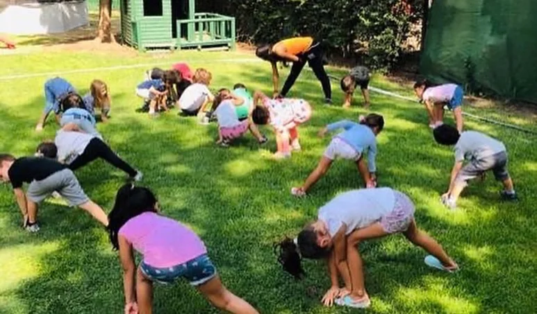 Niños haciendo ejercicios en el pasto durante Summer Girasoles