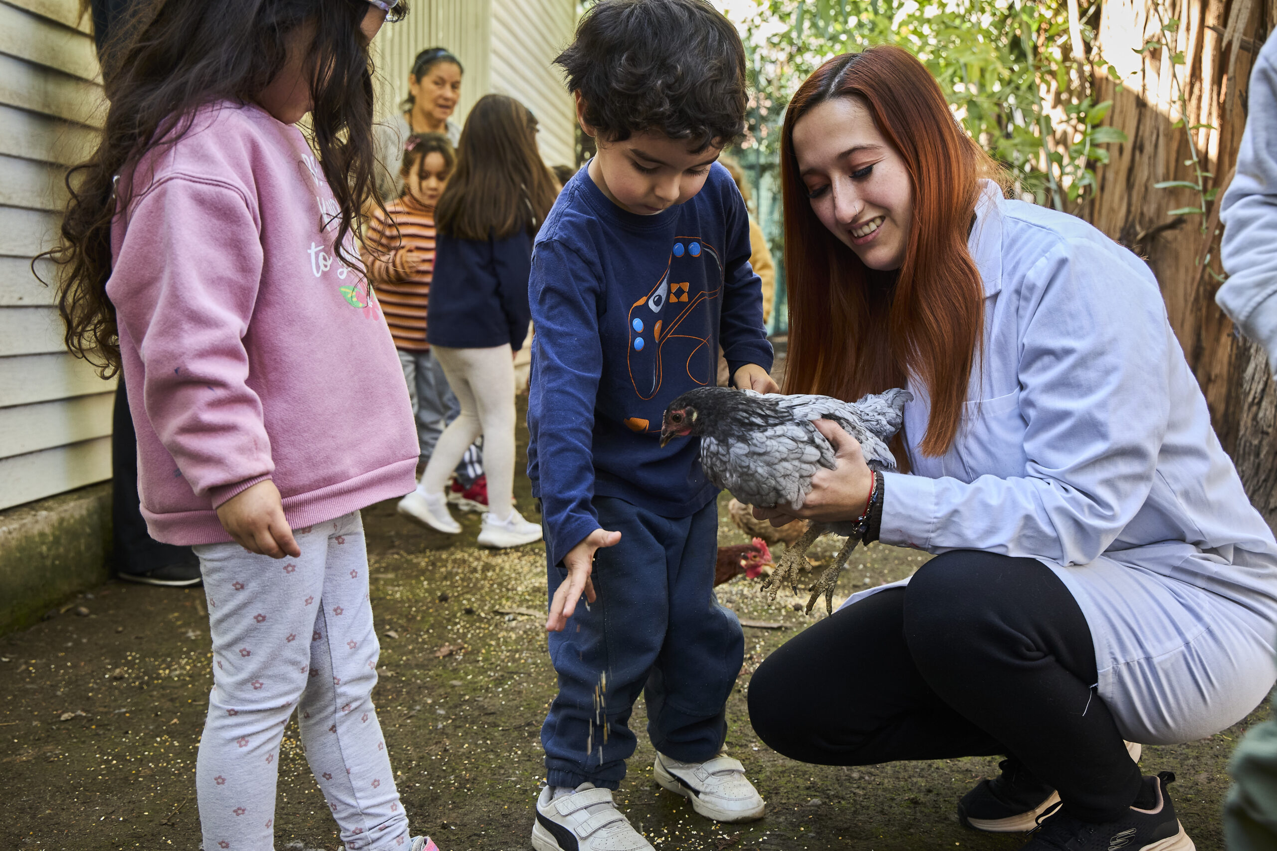 Tía y niños conociendo una gallina